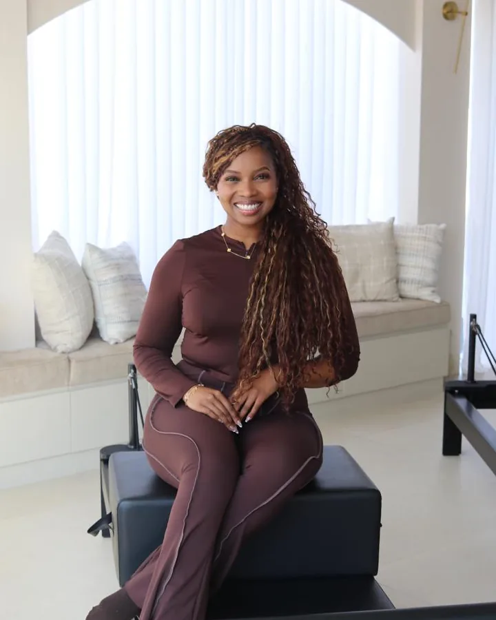 Tanyana, an Elevate instructor, seated on a reformer in the studio.